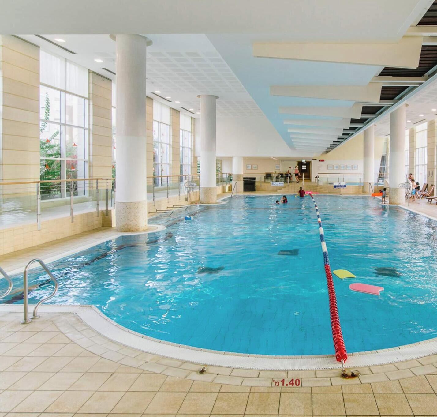 An indoor swimming pool with clear lanes, a lifeguard chair, and a tiled floor.