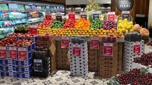 Un supermercat amb diverses fruites i verdures a la vista, com ara pomes, taronjes i plàtans.