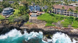 A coastal hotel with multiple buildings, a rocky shoreline, and palm trees. - Direct Ocean Front - Renovation Complete  - EVERYTHING inside is NEW! (Koloa)