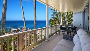 A covered outdoor area with a view of the ocean, featuring a sofa, chairs, and a table. - Direct Ocean Front - Renovation Complete  - EVERYTHING inside is NEW! (Koloa)