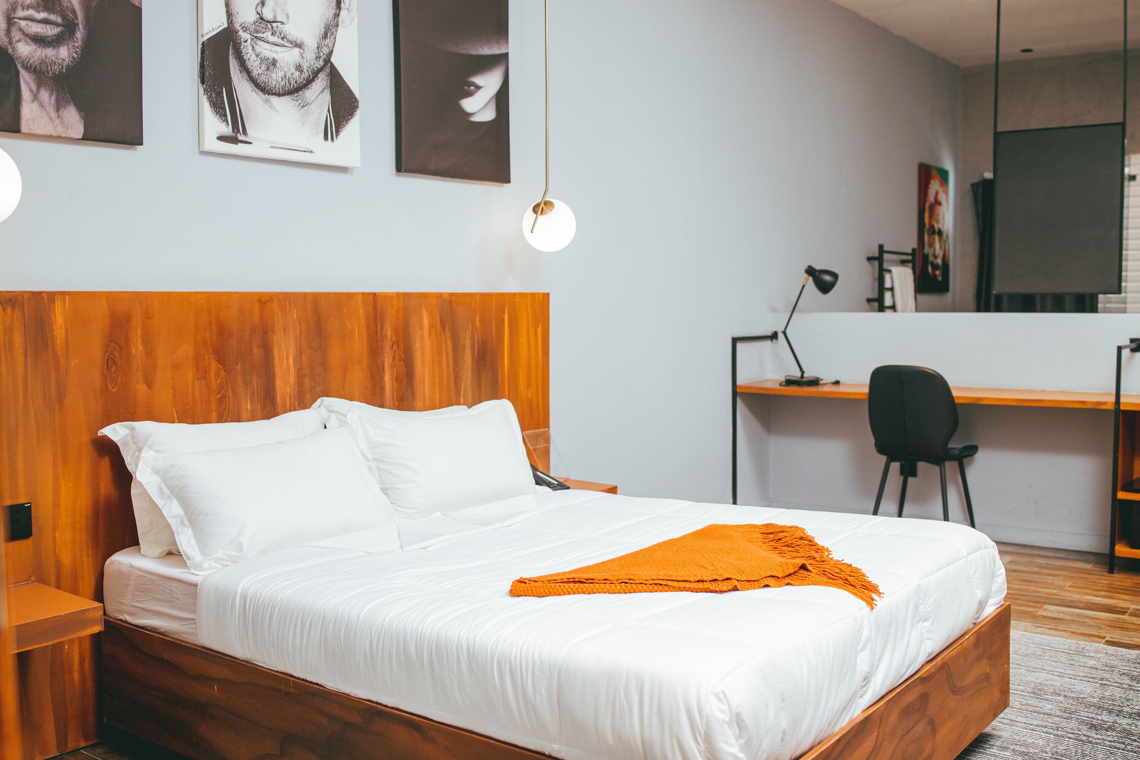 Ein modernes Schlafzimmer mit einem hölzernen Kopfteil, einem weißen Bett und einem Schreibtisch mit Stuhl.