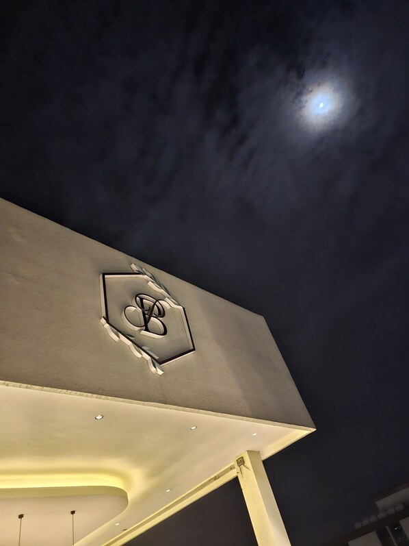 Ein Gebäude mit auffälligem Logo an der Fassade und einem Mond am Himmel.