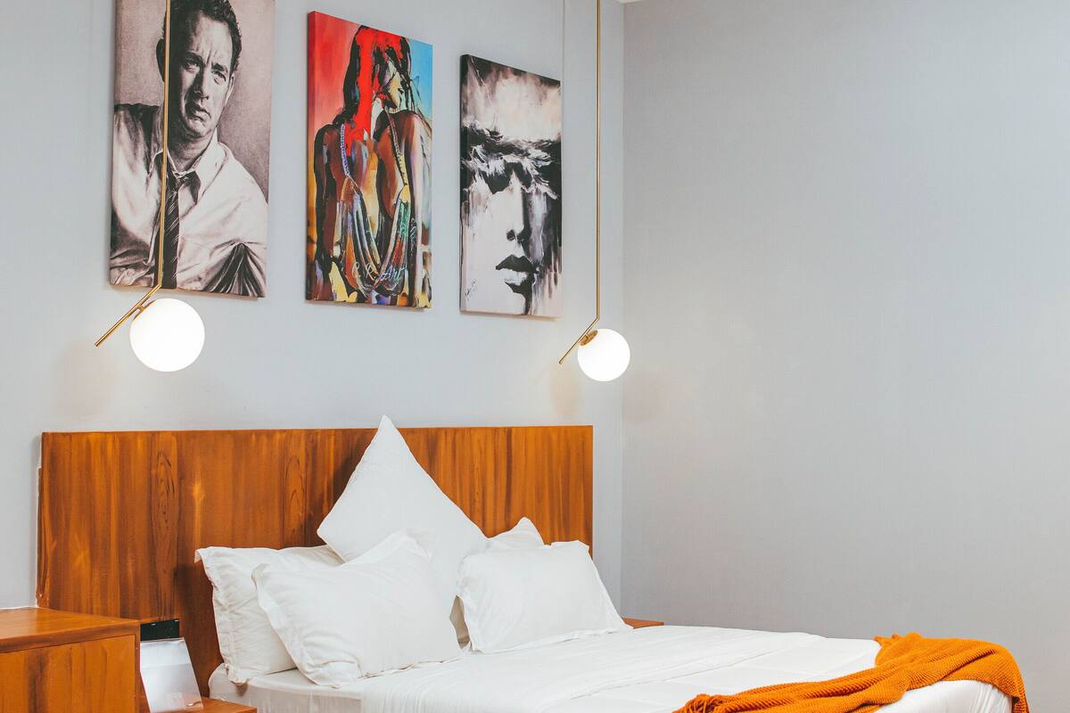 Une chambre à coucher avec un lit en bois, du linge de lit blanc et un ventilateur de plafond.