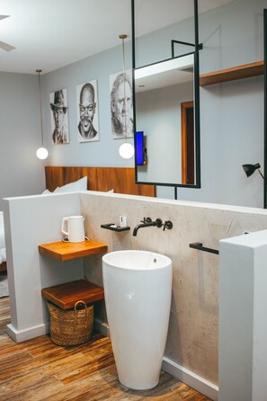 Ein modernes Badezimmer mit einem großen weißen Waschbecken, Holzelementen und einem Bild an der Wand.