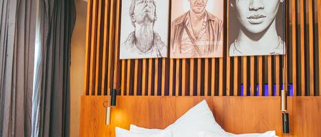 A modern bedroom with a wooden bed frame, a ceiling fan, and wall-mounted artwork.