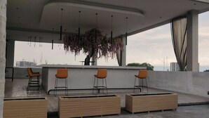 Ett modernt utomhusområde med sittplatser, en bar, bekväma stolar och hängande växter.