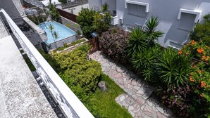 A residential building with a swimming pool, stone pathway, and lush greenery.