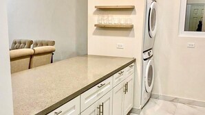 Een moderne keuken met witte kastjes, een ingebouwde wasmachine en een aanrecht met een lamp erboven.