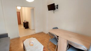Ein Wohnzimmer mit einer Couch, einem kleinen Tisch und einem an der Wand befestigten Fernseher.