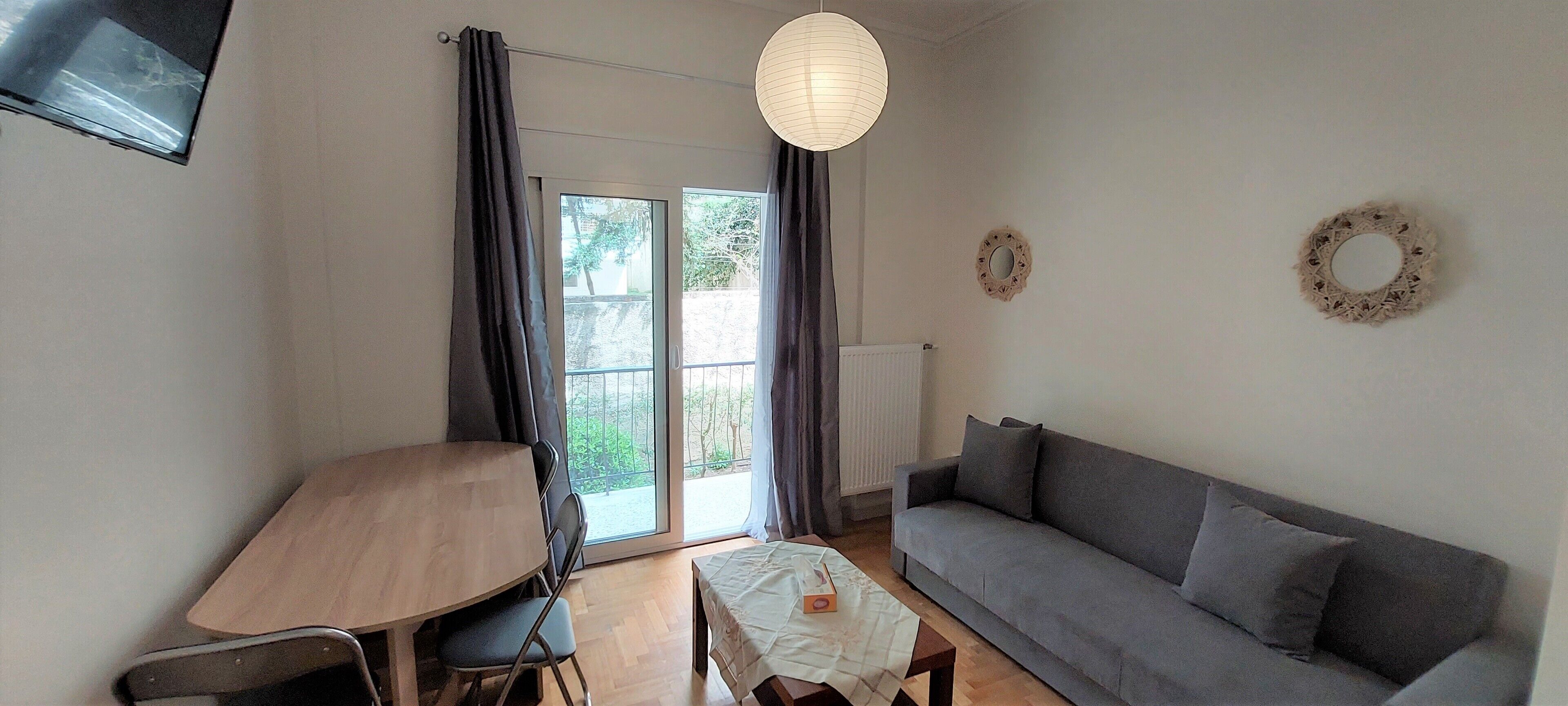 A living room with a grey sofa, a wooden table, and a white tablecloth.