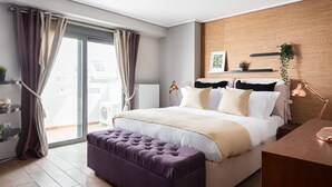 Ein modernes Schlafzimmer mit einem großen Bett, einer Wandpaneele aus Holz, einem Balkon mit Vorhängen und einem Schreibtisch mit Lampe.