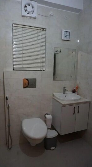 Bathroom features a toilet, sink, and mirror, with a window and air conditioning unit.