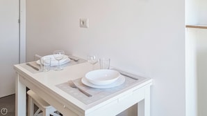 A clean, white dining table set with plates, bowls, wine glasses, and cutlery.