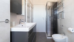 A modern bathroom with a glass shower enclosure, a white sink, and a toilet.