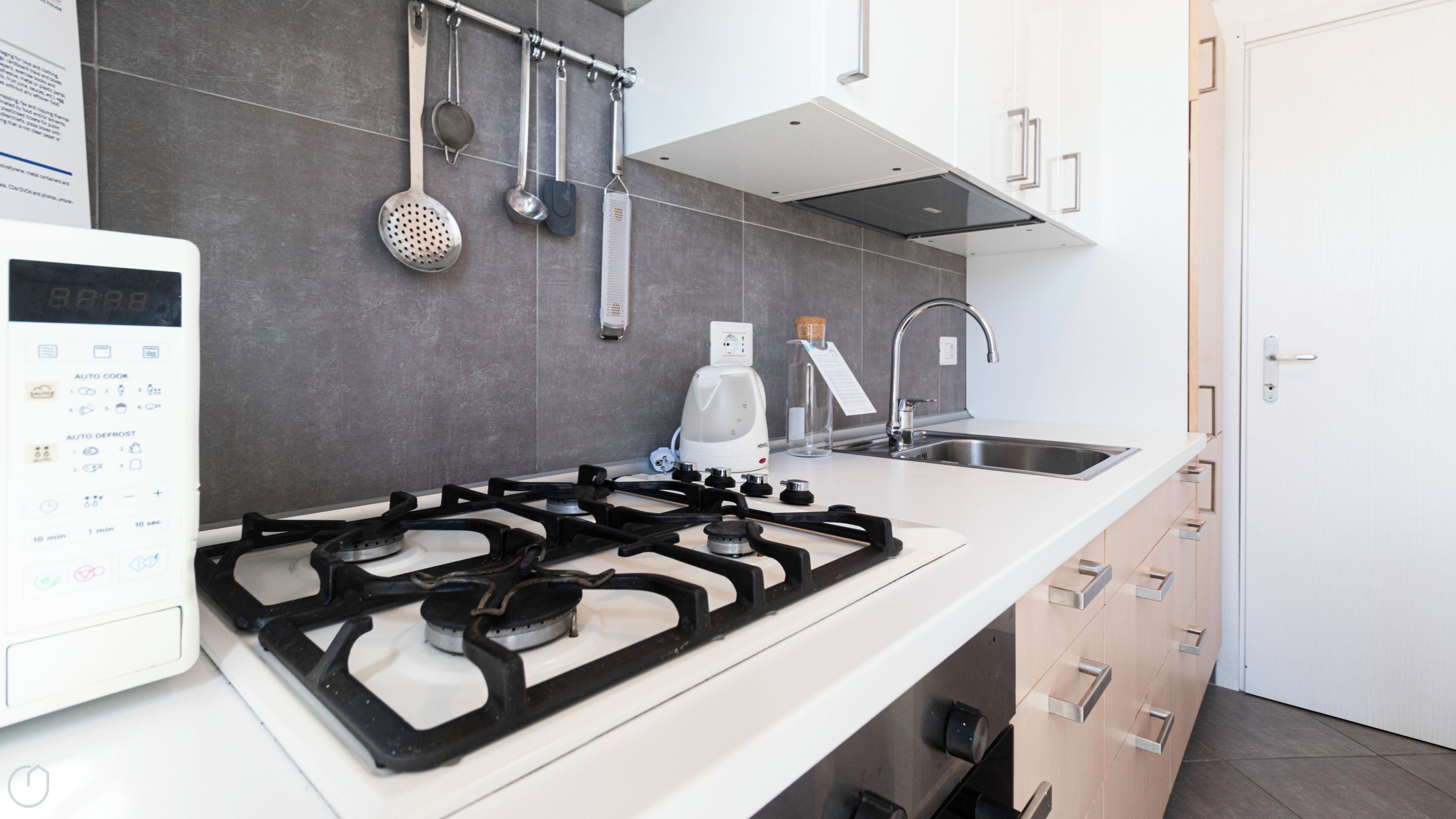 Una cucina moderna con un fornello a gas, una macchina per il caffè e un lavandino.