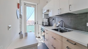 A modern kitchen with white cabinets, a stainless steel sink, and a built-in oven.
