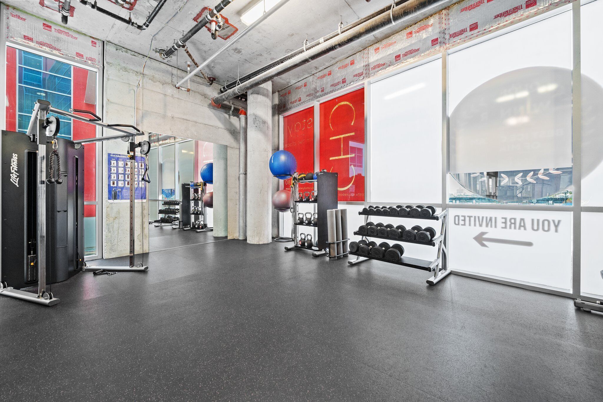 A gym with exercise equipment, a punching bag, and a sign indicating a direction.