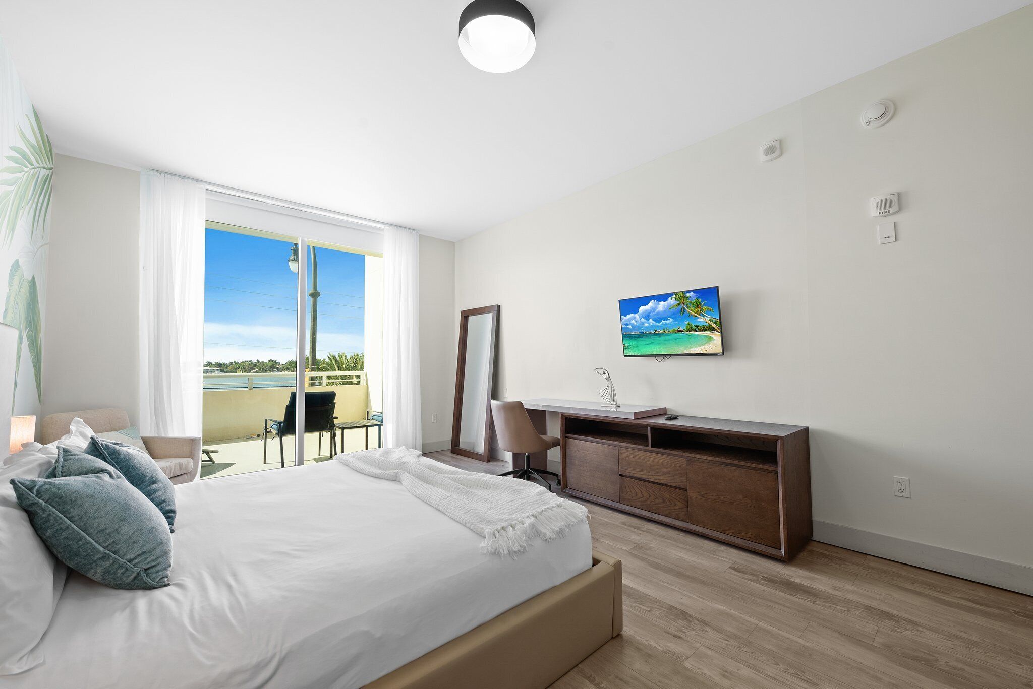 Une chambre d’hôtel avec un grand lit, un bureau doté d’un lavabo, une chaise et un téléviseur fixé au mur.
