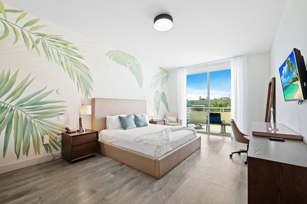 Een moderne hotelkamer met een groot bed, een bureau en een balkon met uitzicht.