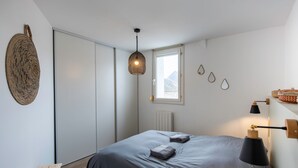 Een slaapkamer met een bed, nachtlampjes, een raam en een radiator.
