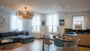 Een moderne woonkamer met een hoekbank, een eettafel met stoelen, en een keuken met een bar.