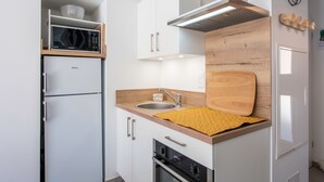 A compact kitchen with a microwave, sink, and wooden countertop. - Bibifoc Baie - au coeur de la Baie de la Somme (Saint-Valery-sur-Somme)