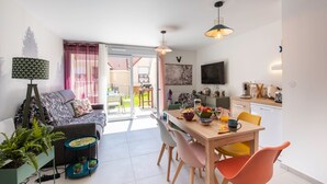 A modern living room with a sofa, dining table, chairs, and a kitchen area. - Bibifoc Baie - au coeur de la Baie de la Somme (Saint-Valery-sur-Somme)