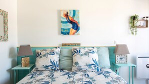 A bedroom with a bed, floral-patterned bedding, a painting on the wall, and two bedside tables with lamps. - Bibifoc Baie - au coeur de la Baie de la Somme (Saint-Valery-sur-Somme)
