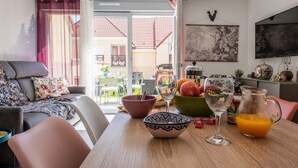A cozy living room with a sofa, a dining table with a bowl, a wine glass, and a pitcher of orange juice. - Bibifoc Baie - au coeur de la Baie de la Somme (Saint-Valery-sur-Somme)