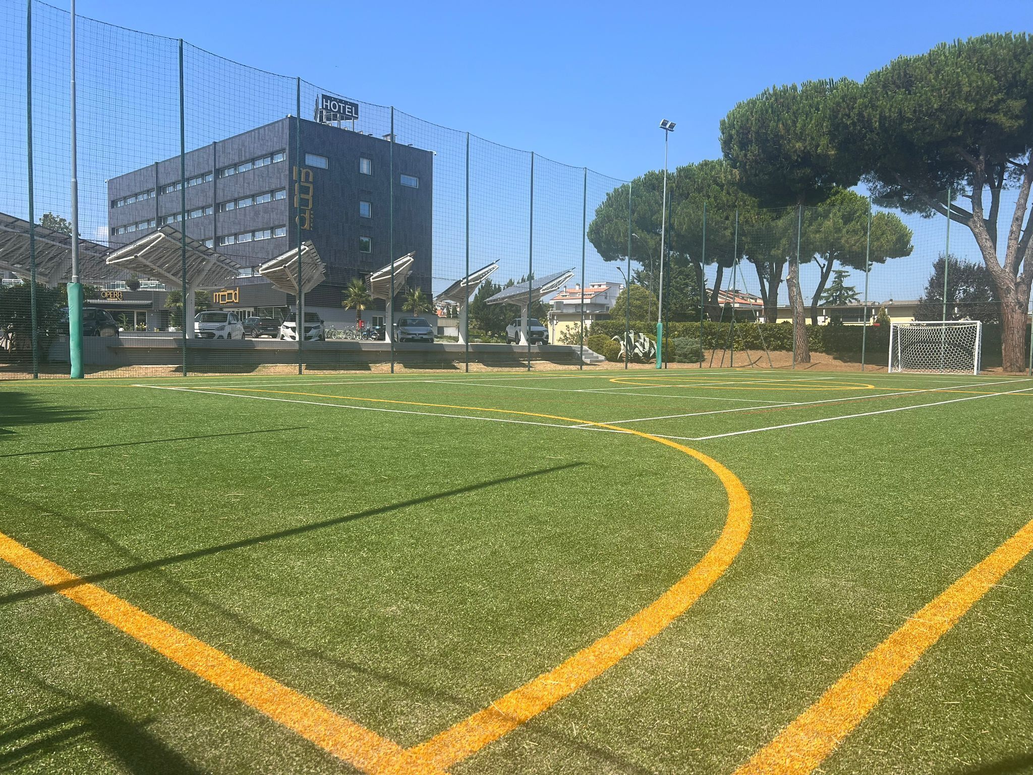 A sports field with a building labeled "HOTEL" in the background.