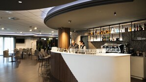 Zona de bar moderna con una barra curva, taburetes y una variedad de botellas de licor.