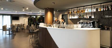 A modern bar area with a curved counter, bar stools, and a variety of liquor bottles.