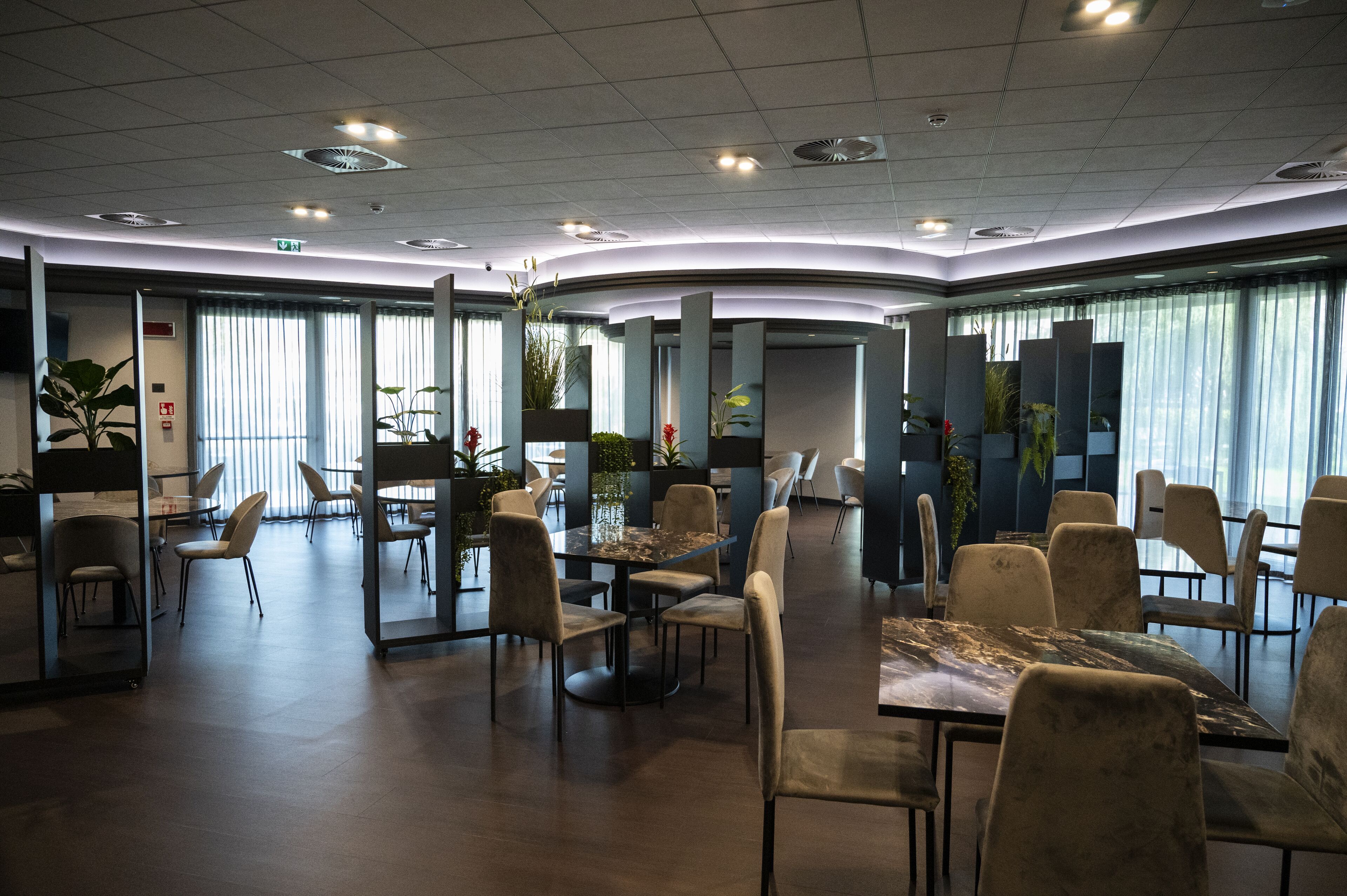 A modern hotel lobby with a curved layout, multiple seating areas, and large windows allowing natural light.