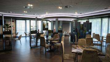 A modern hotel lobby with a curved layout, multiple seating areas, and large windows allowing natural light.