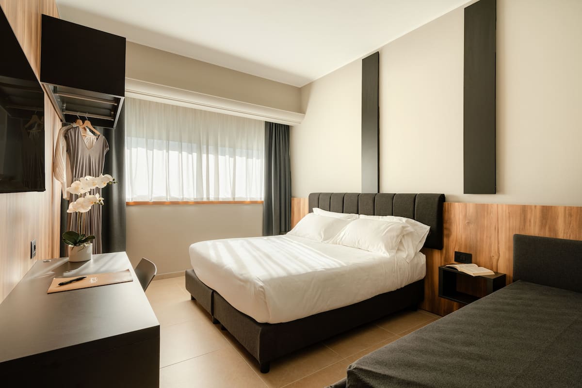 Un dormitorio moderno con cama, mesita de noche y escritorio con silla.