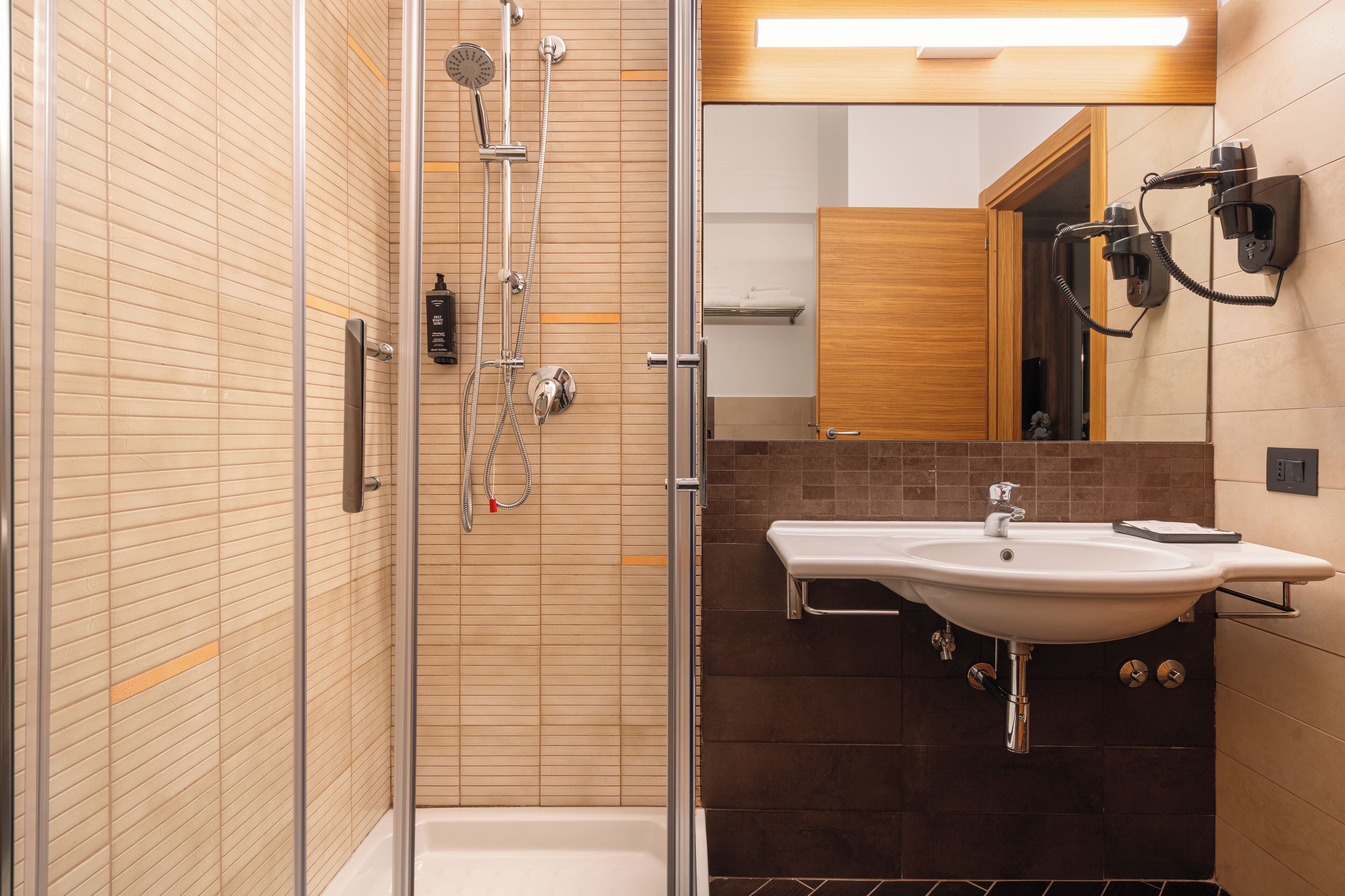 A modern bathroom with a glass-enclosed shower, a white sink, and a wooden vanity.