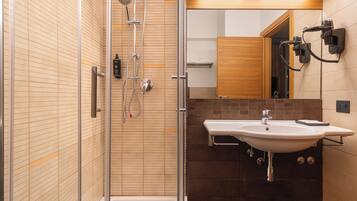 Une salle de bain moderne avec une douche à parois de verre, un lavabo blanc et un meuble-lavabo en bois.