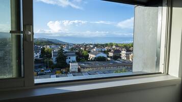 Une vue depuis une fenêtre donnant sur un quartier résidentiel, avec des maisons et un ciel dégagé.