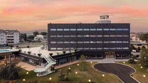 Un hotel moderno con techo plano, varios pisos y un letrero que indica que es un hotel.