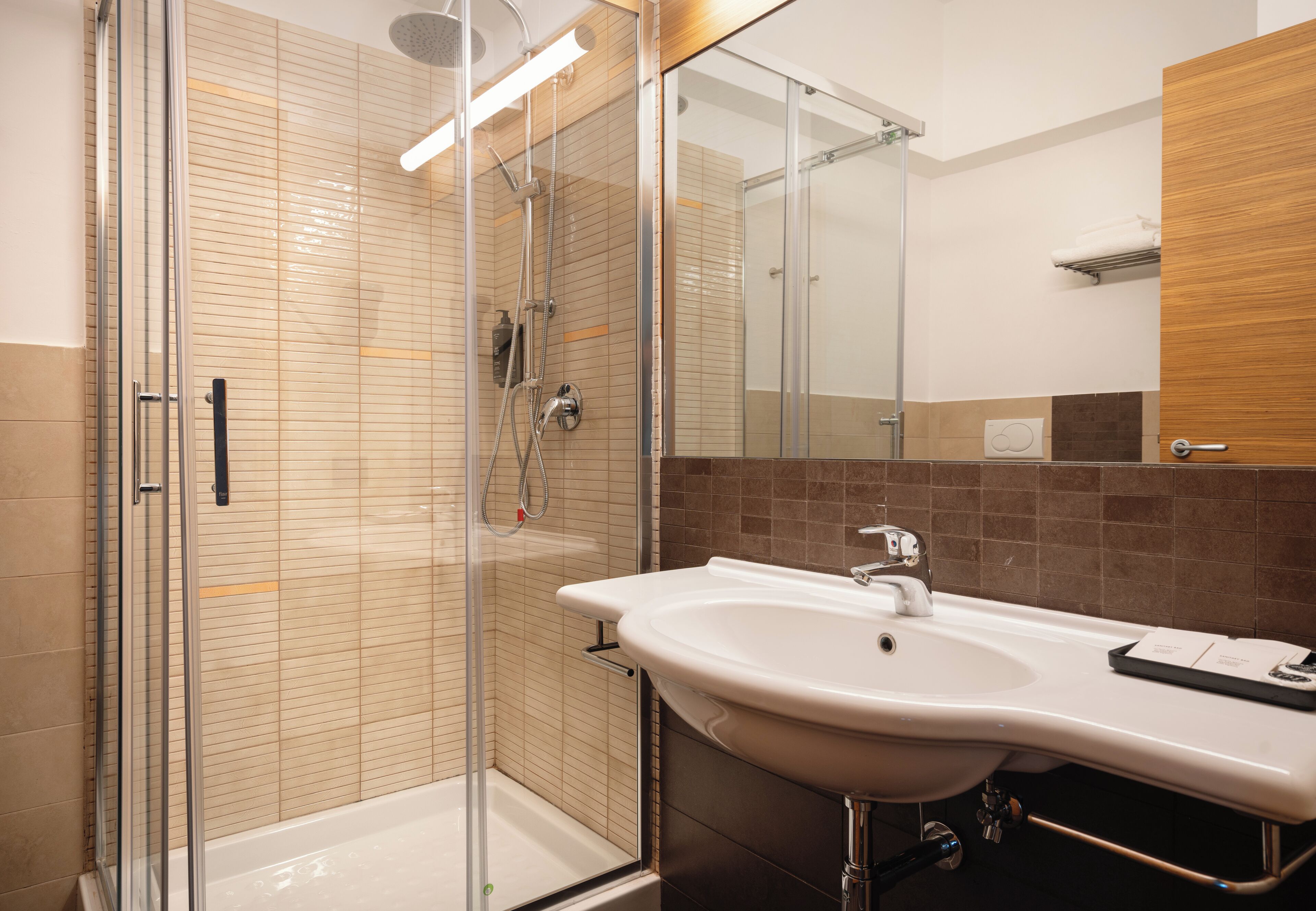Un baño moderno con ducha acristalada, un lavabo blanco y un espejo.