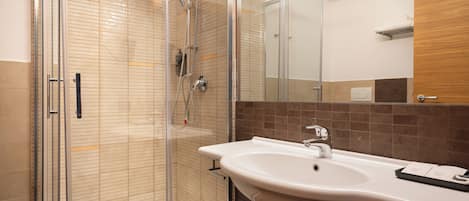 A modern bathroom with a glass-enclosed shower, a white sink, and a mirror.