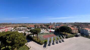 Vista aérea de uma área residencial com casas, quadra de tênis e painéis solares.