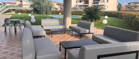 An outdoor patio area with modern furniture, a pool, and a view of residential buildings.