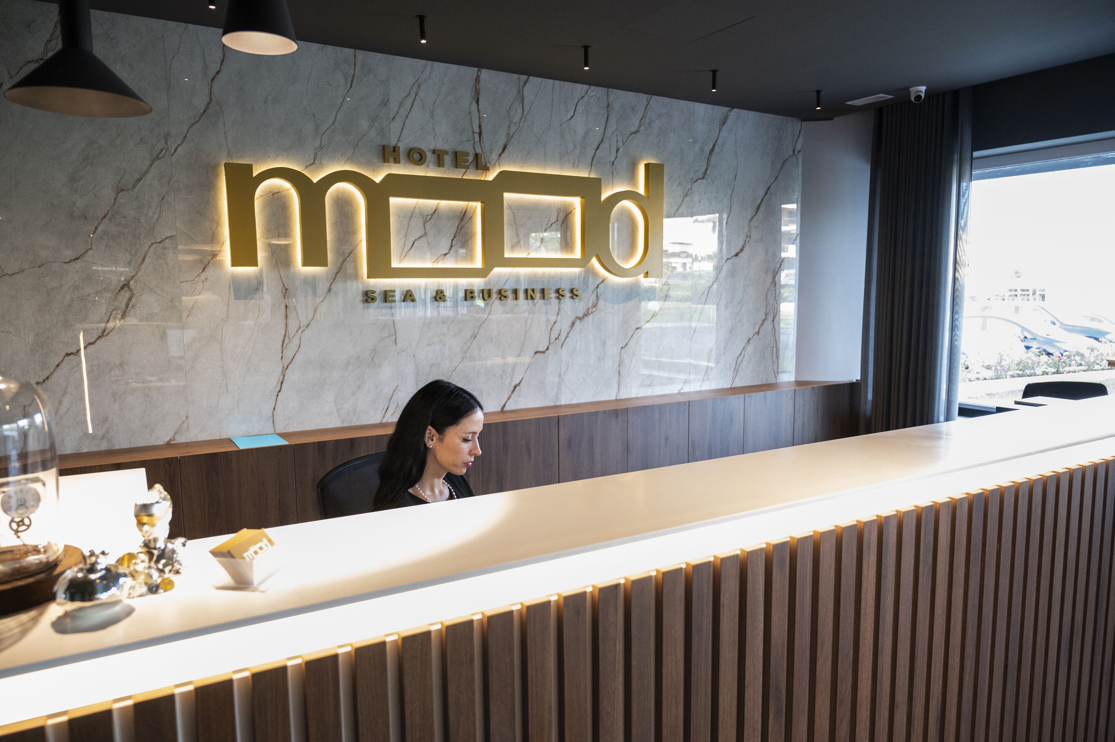 A hotel reception desk with a marble wall and a modern design.