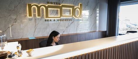 A hotel reception desk with a marble wall and a modern design.
