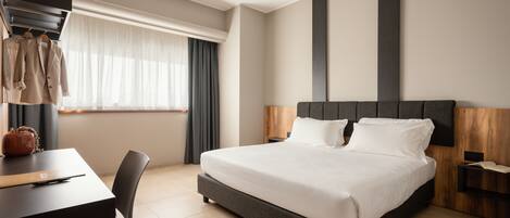 Une chambre d’hôtel moderne, dotée d’un grand lit, d’un bureau avec une chaise, d’une armoire et d’une fenêtre avec des rideaux.