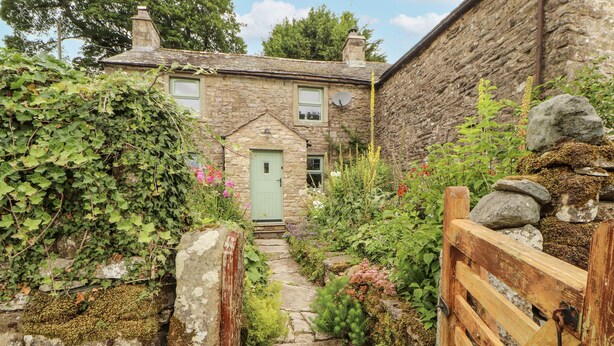 A stone house with a green door, a stone pathway, and a wooden gate. - White House (Penrith)