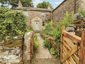A stone house with a green door, a stone pathway, and a wooden gate. - White House (Penrith)