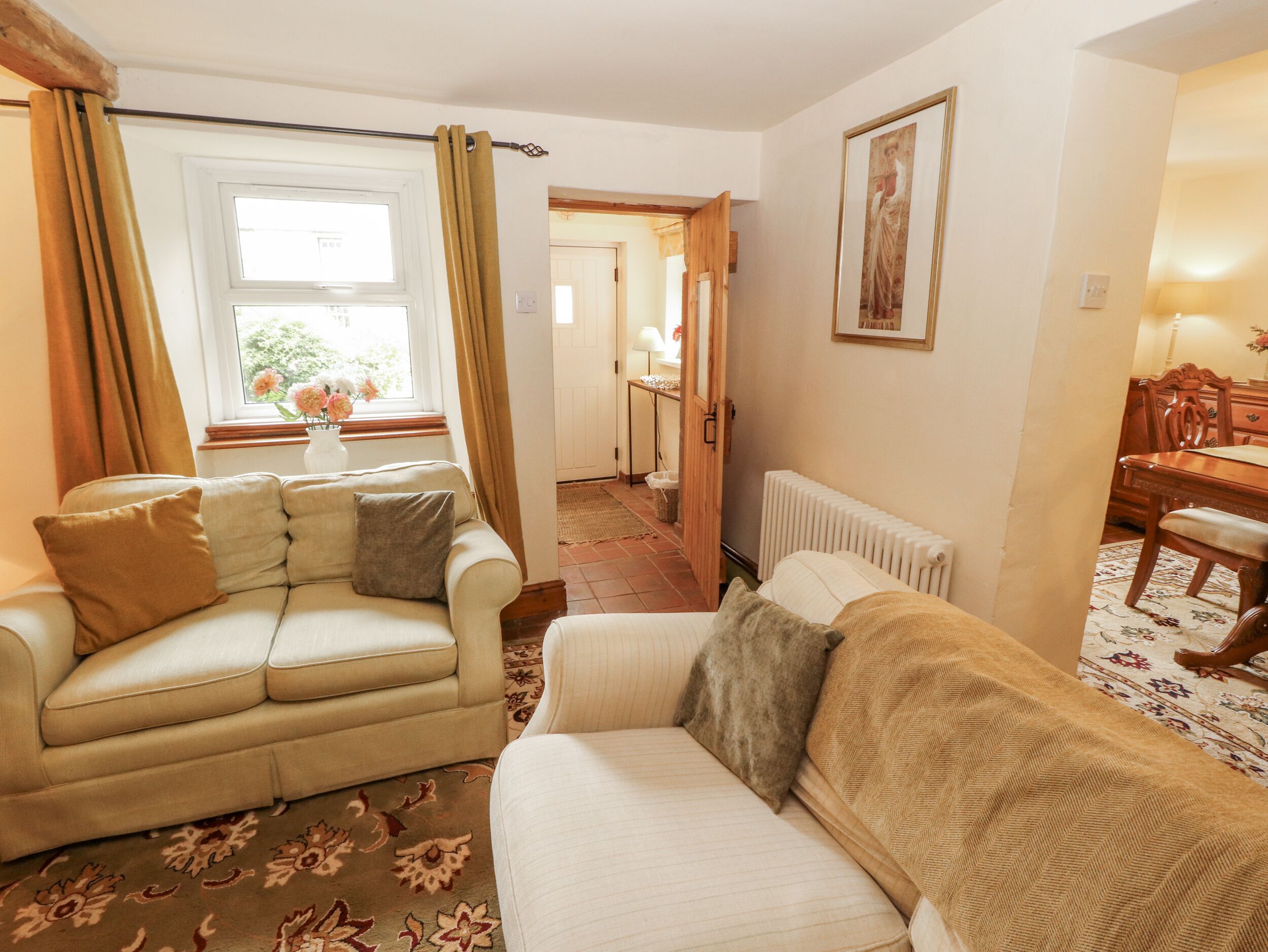 A living room with two sofas, a radiator, a framed picture on the wall, and a window with curtains.
