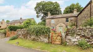 A stone house with a green door, a stone wall, and a wooden gate. - White House (Penrith)
